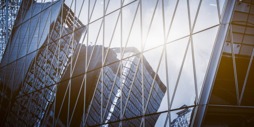 Image of buildings being reflected off of another glass building.